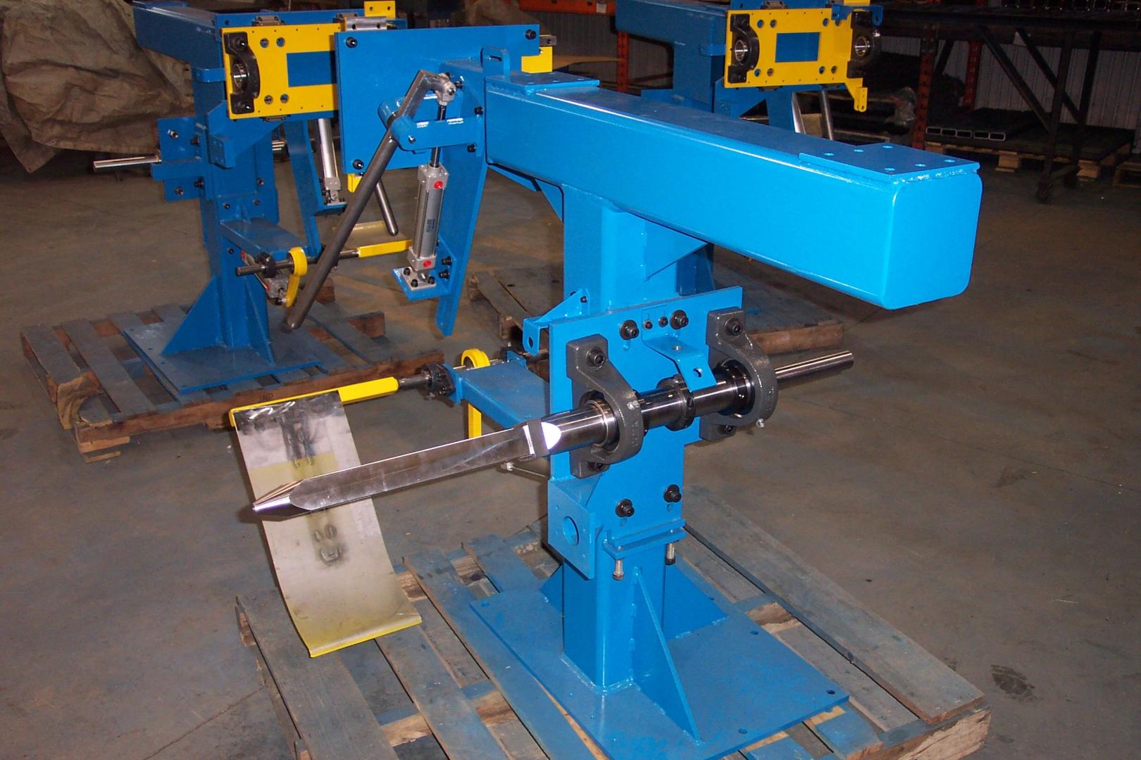 Two blue industrial machinery stands with yellow accents, mounted on wooden pallets in a warehouse setting.
