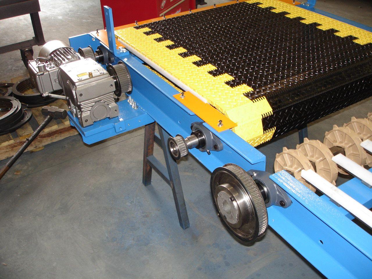 A close-up of a blue industrial conveyor belt system with a yellow and black modular track, supported by a metal frame.