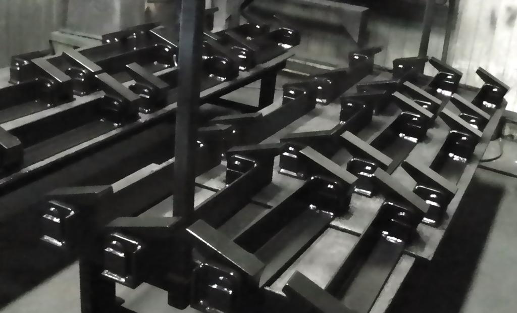 A group of black, welded metal industrial components arranged in rows on a workshop floor.