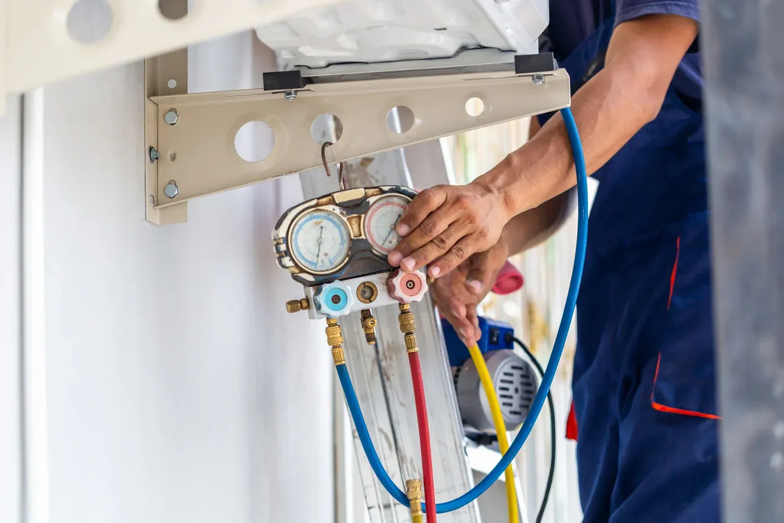 A technician uses a manifold gauge set to service an air conditioning unit.