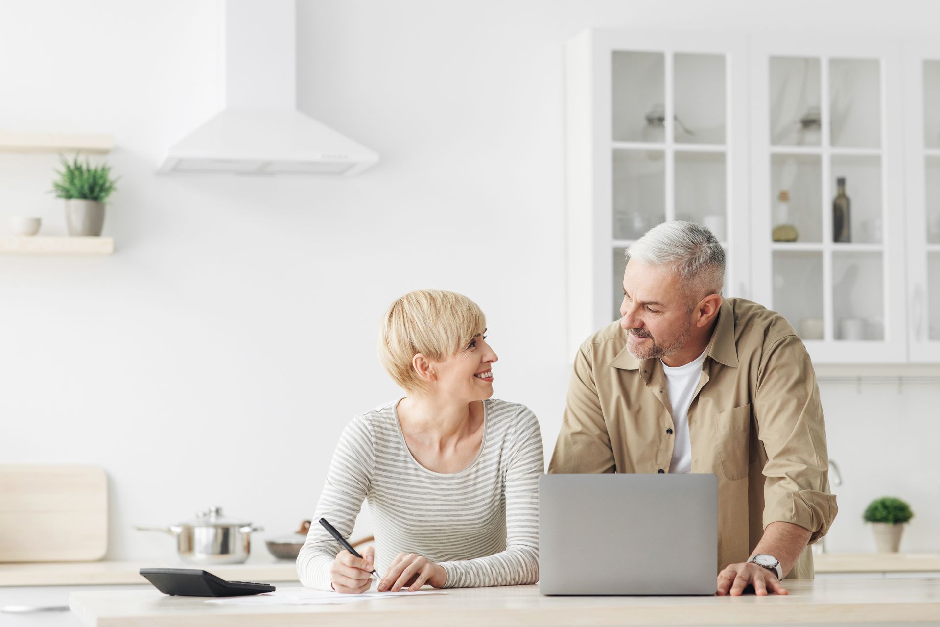 senoir couple spouses uses laptop in kitchen