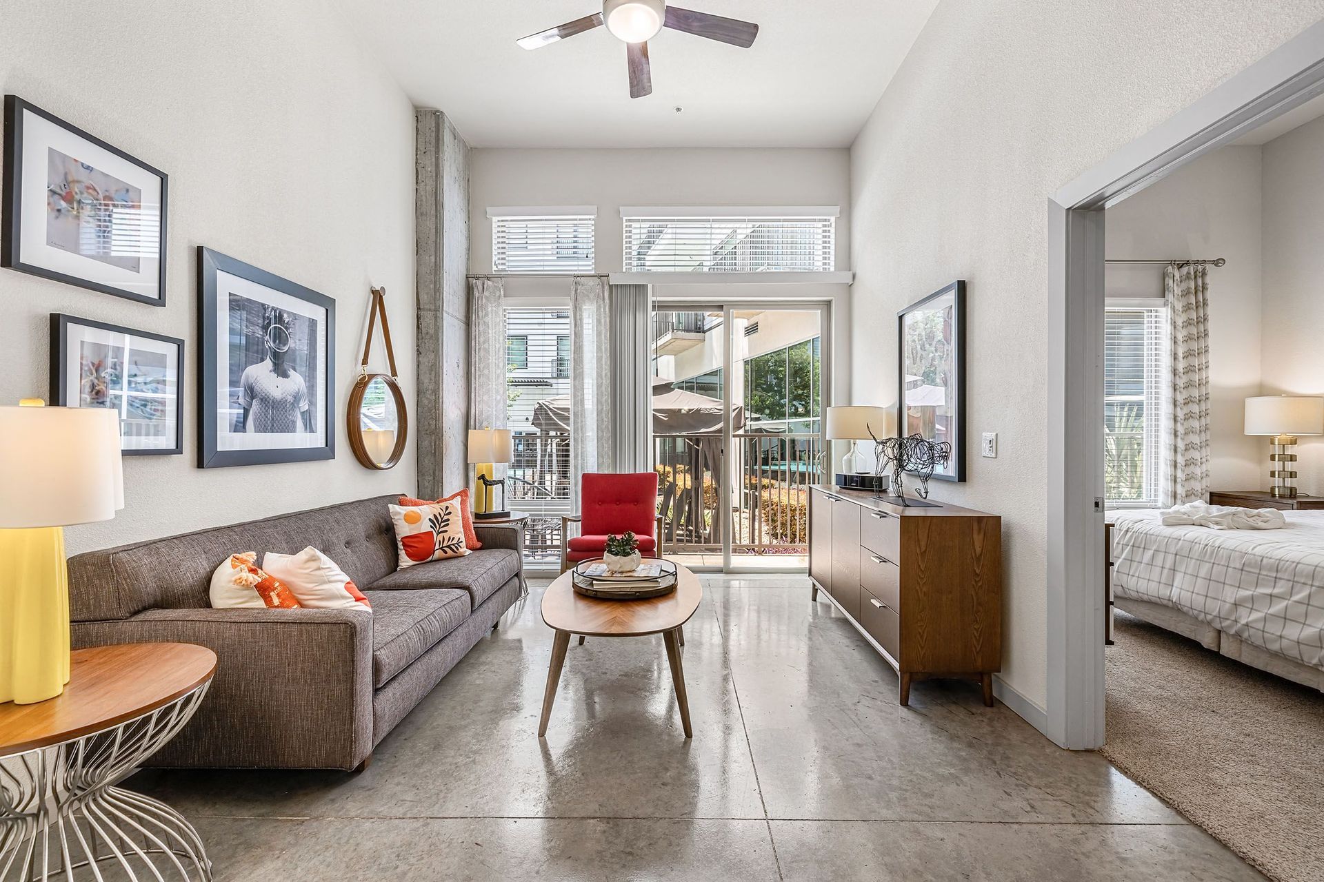 Bright living room with gray sofa, coffee table, artwork, and sliding doors to a balcony at Marq on Burnet
