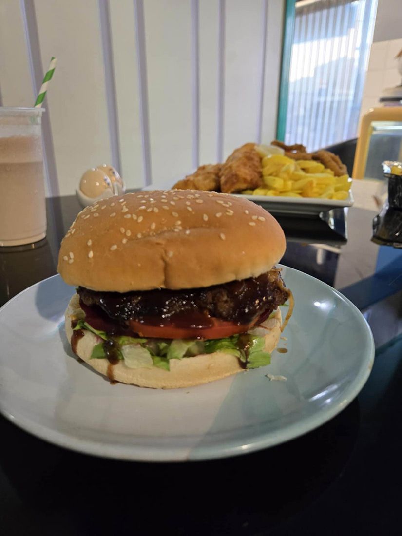 A hamburger is sitting on a white plate on a table — Deep Sea Delights in Taree, NSW