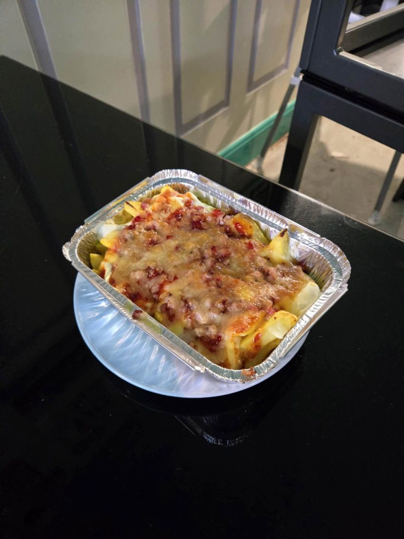 A Foil Container Filled With Food is Sitting on a Plate on a Table — Deep Sea Delights in Taree, NSW