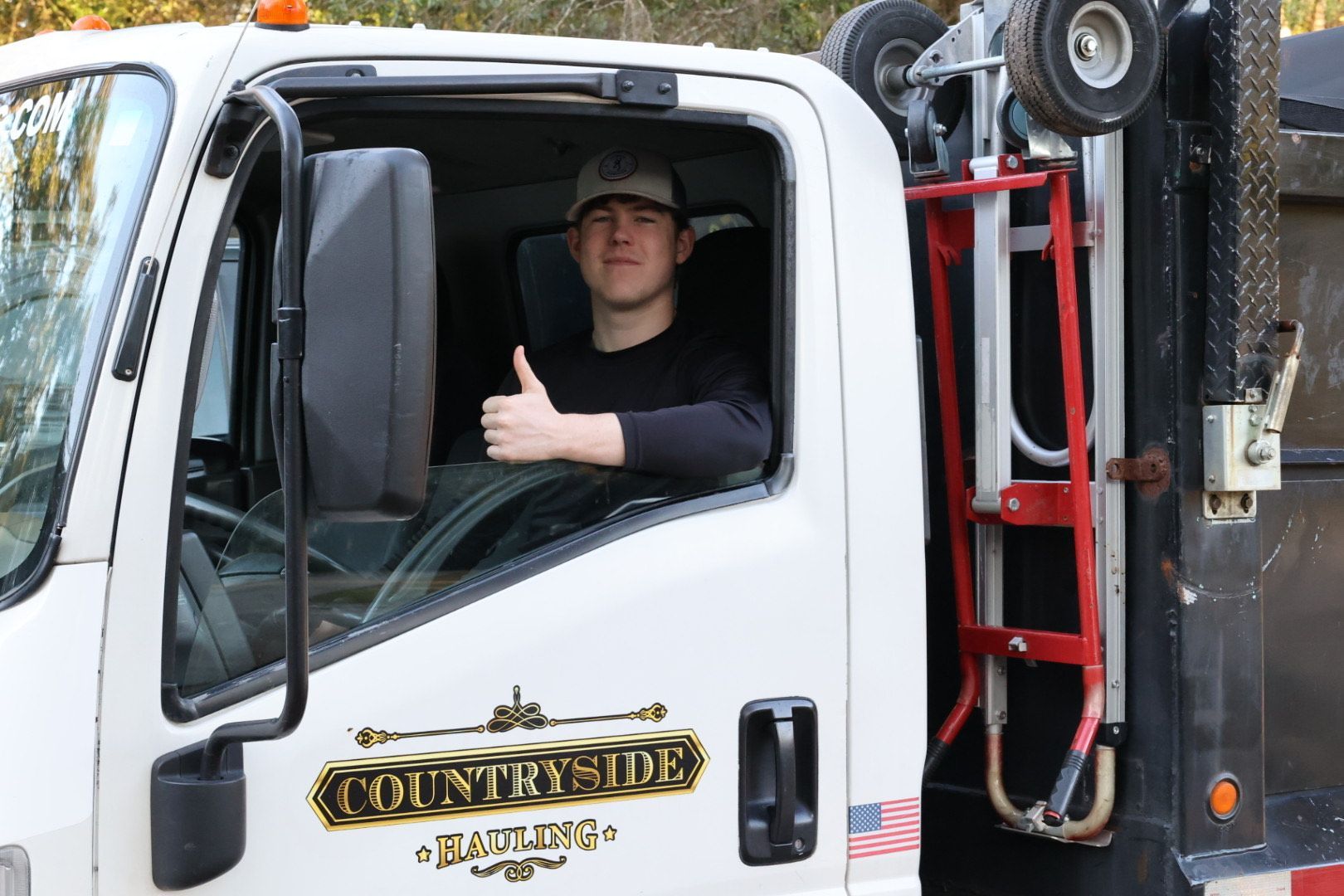 A man is giving a thumbs up while driving a dump truck.