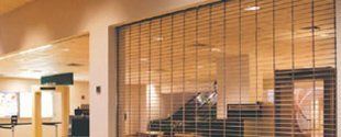 Lobby interior with a wood-slatted glass partition and warm overhead lighting