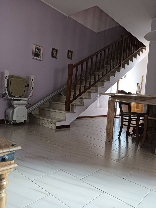 Scala in una casa con pareti viola, pavimento in piastrelle bianche e tavolo da pranzo vicino a una finestra luminosa.
