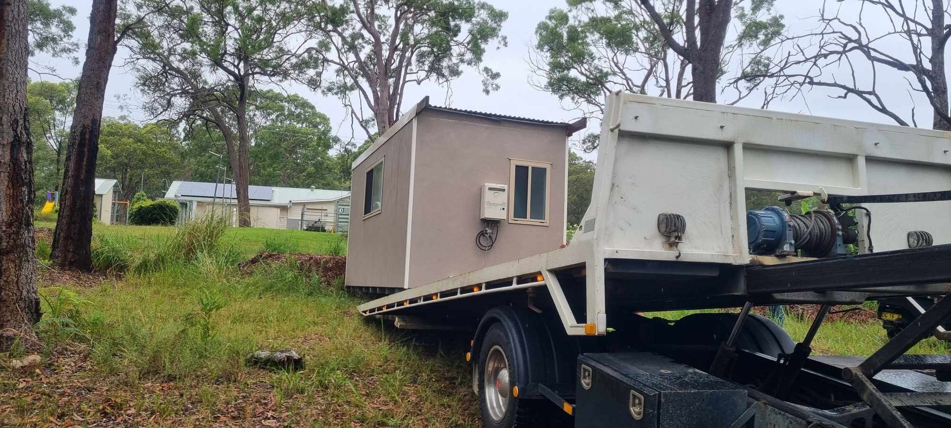 A Tow Truck is Carrying a Small House on the Back of It — A Towing Service In Forster, NSW