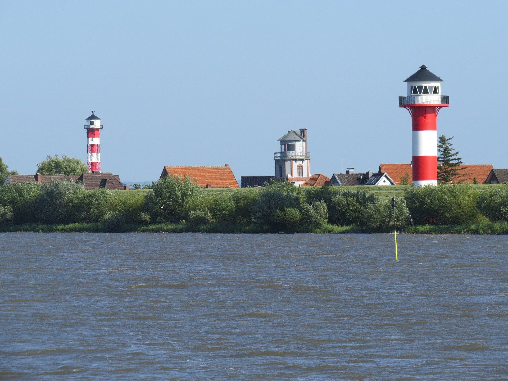 Rot-weiße Leuchttürme entlang einer Küste über blauem Wasser unter klarem Himmel