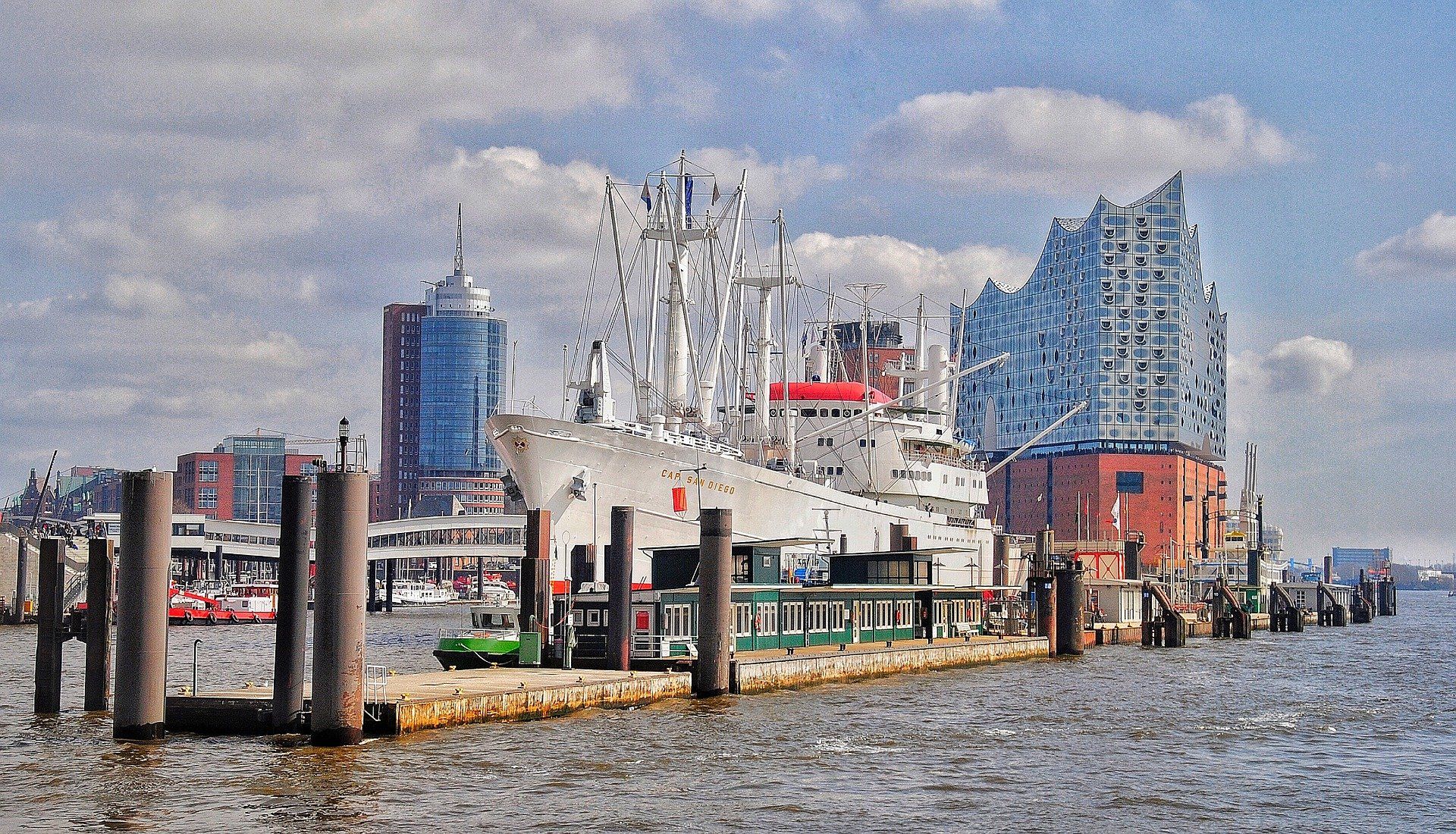 Pier am Wasser mit einem festgemachten Boot und farbenfrohen Stadtgebäuden unter einem bewölkten Himmel
