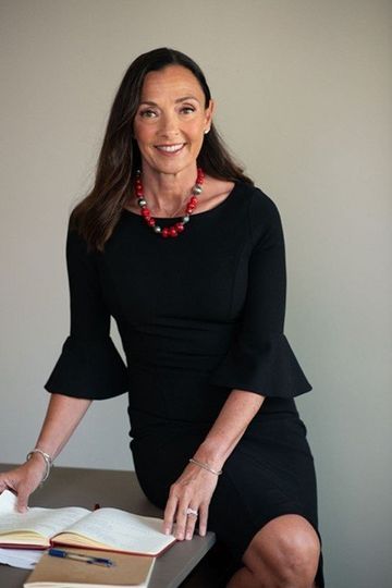 A woman in a black dress is sitting at a desk.