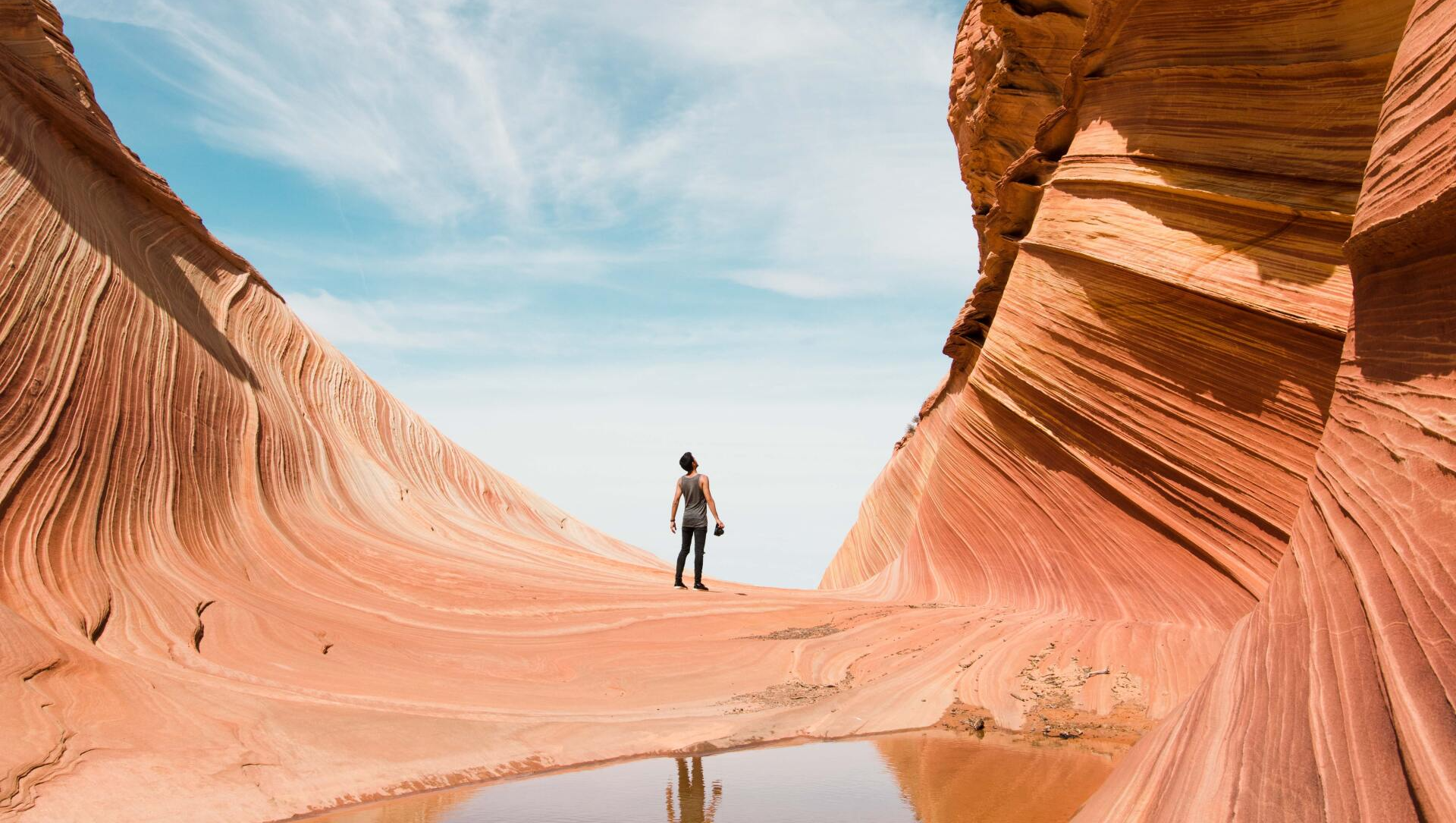 A man is standing in the middle of a canyon in the desert.