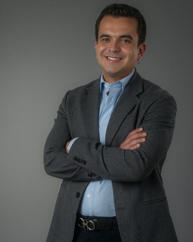 JC con blazer gris y los brazos cruzados