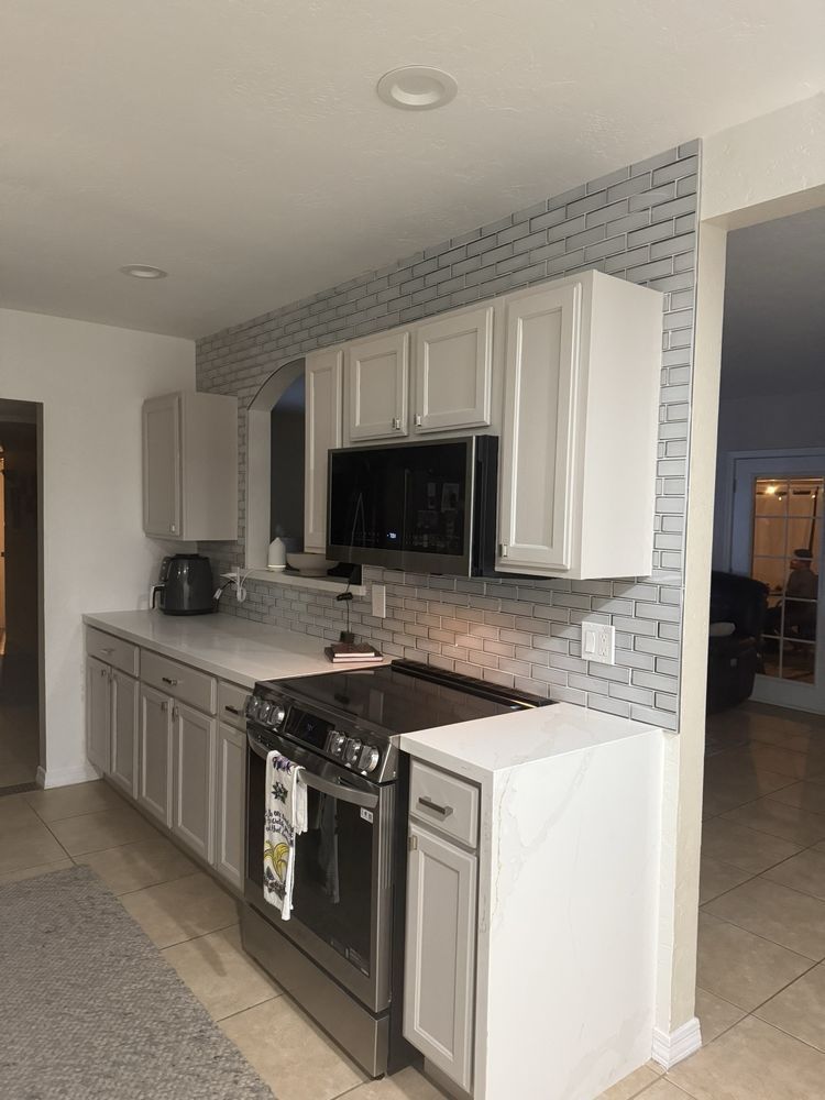 A kitchen with white cabinets , a stove and a microwave.