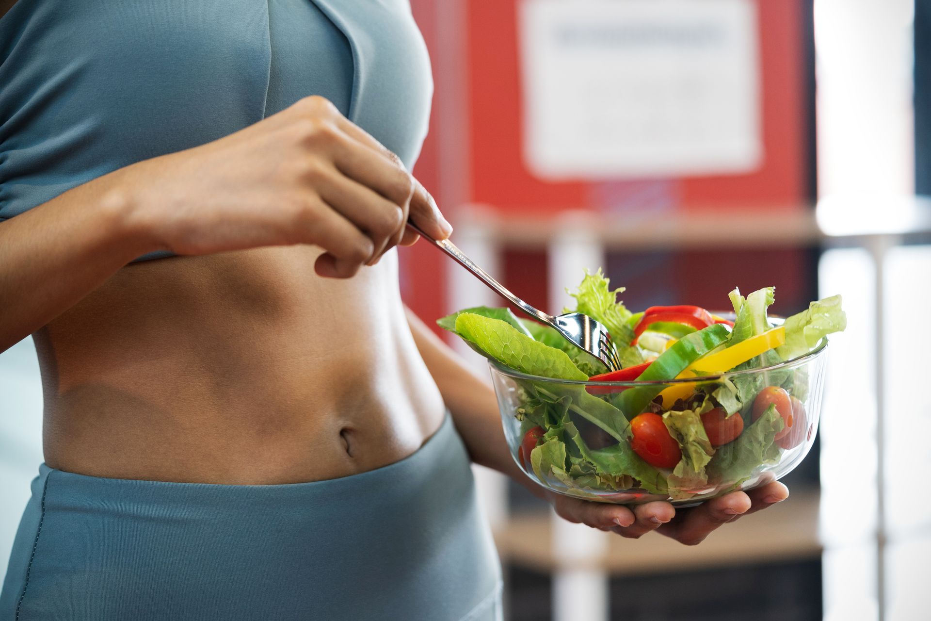 A woman is eating a salad with a fork from a bowl.