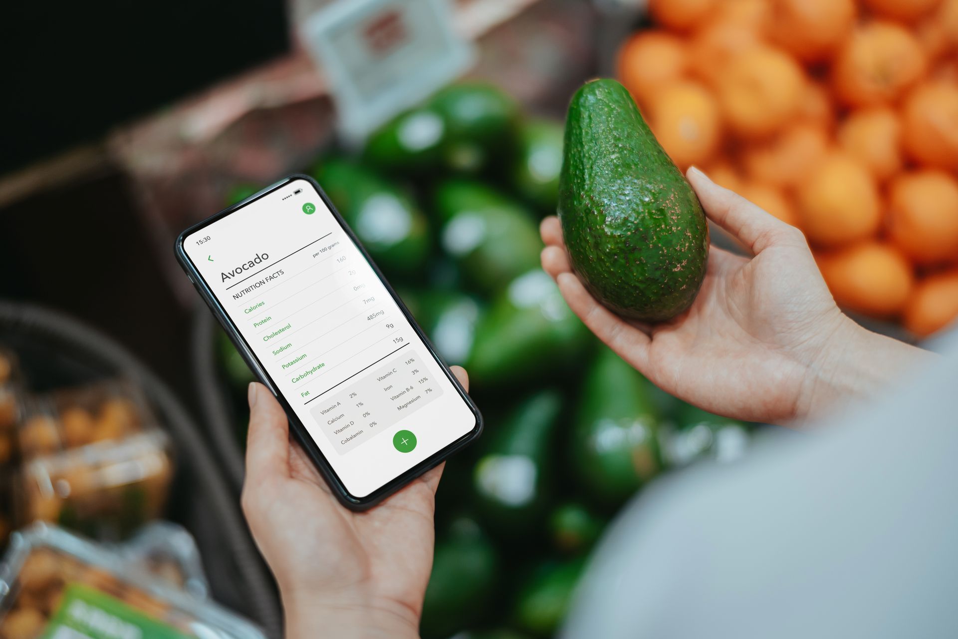 A person is holding an avocado and looking at a cell phone.