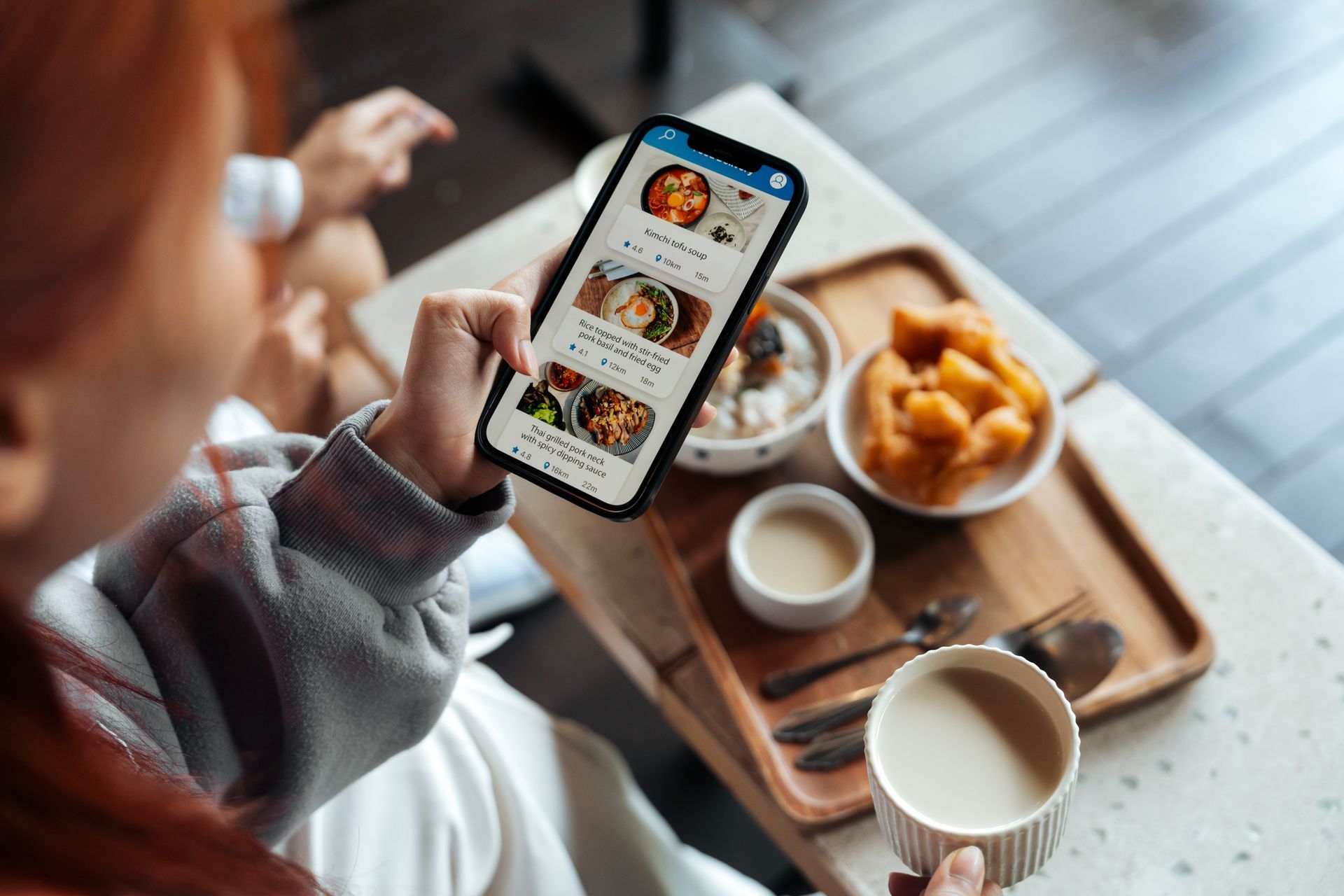 A person is holding an avocado and looking at a cell phone.