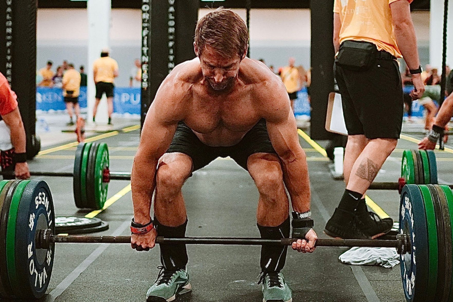 A man is lifting a barbell in a gym.
