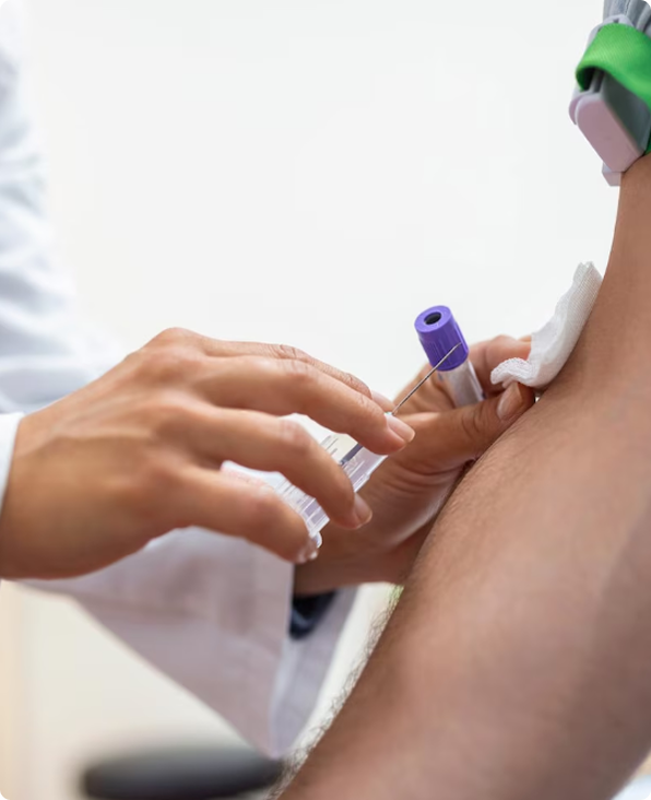 Healthcare worker taking blood from a patient’s arm with a syringe and vial
