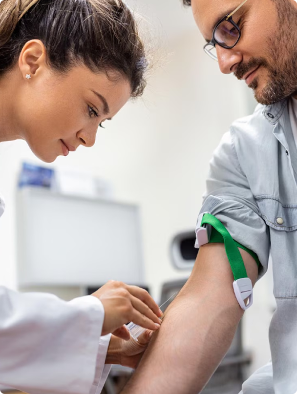 Clinician drawing blood from a patient’s arm in a medical exam room