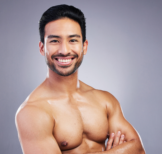 Smiling shirtless man with arms crossed against a gray background