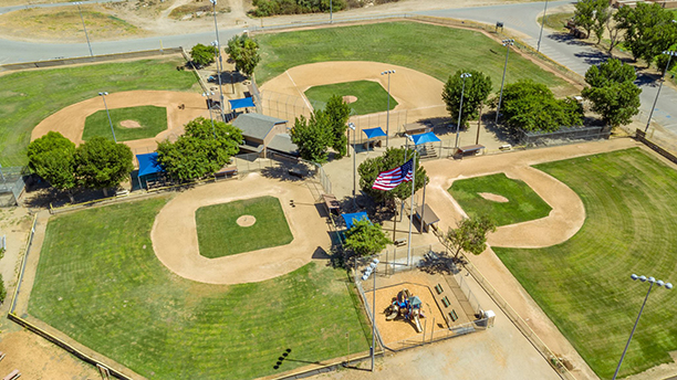 Aerial view of a baseball complex with multiple diamond fields, green grass, and dugout areas.