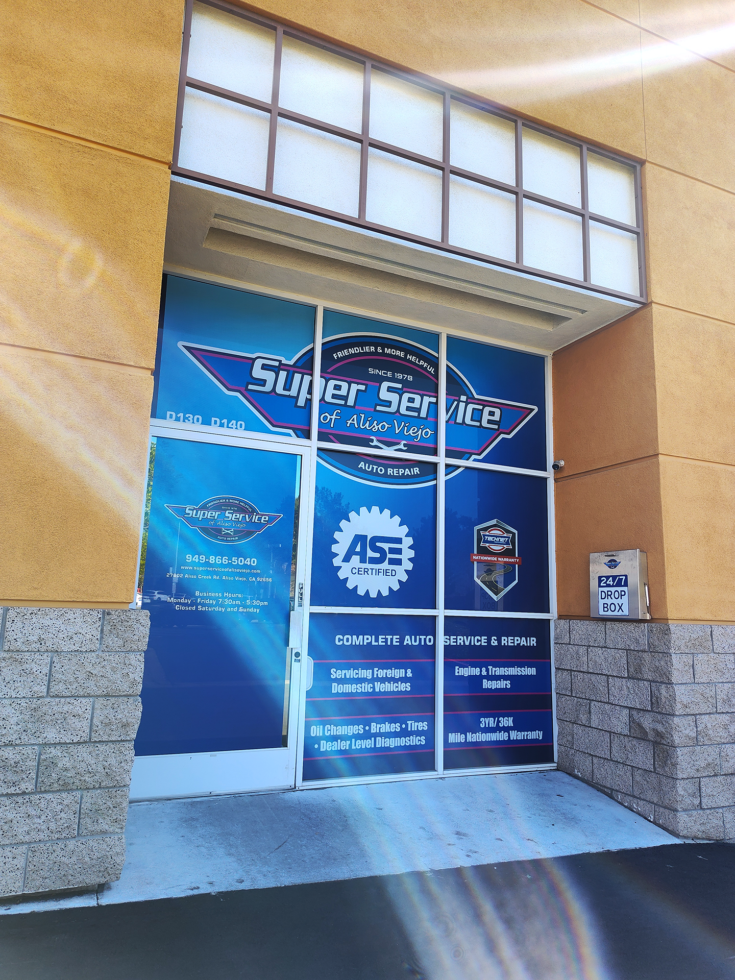 Entrance to Super Service auto shop with logo on the glass door and an ASE certification symbol. | Super Service of Aliso Viejo
