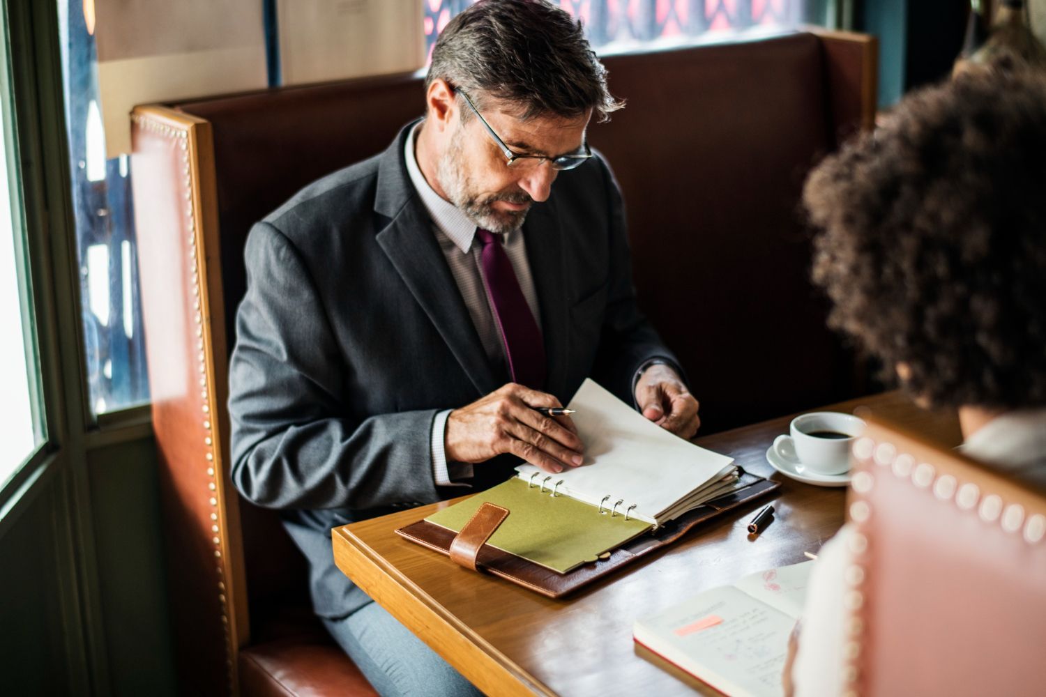 Two business professionals in suits reviewing documents, discussing strategy.