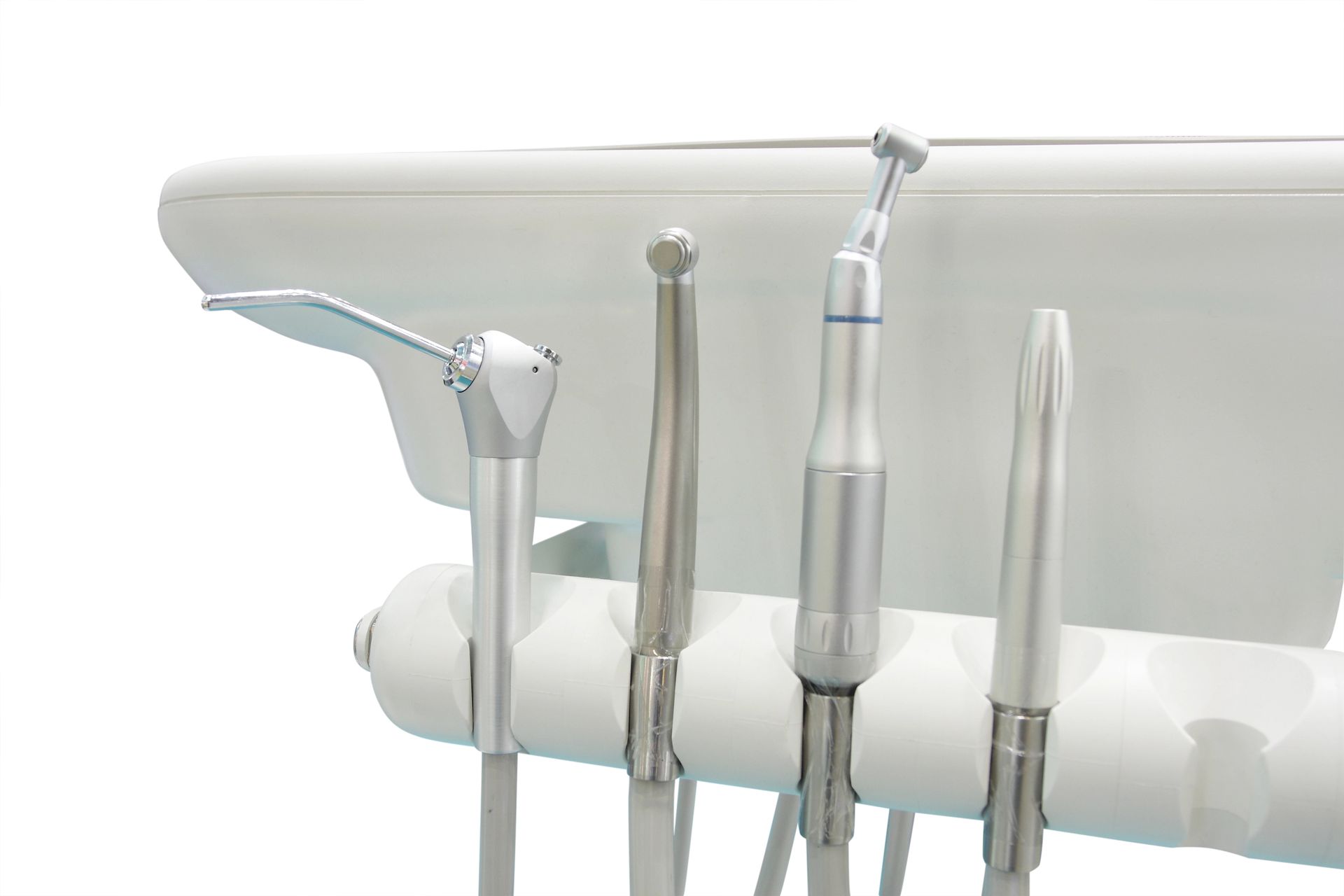 Primer plano de herramientas dentales en un soporte, incluido un raspador, una sonda y una pieza de mano de alta velocidad.
