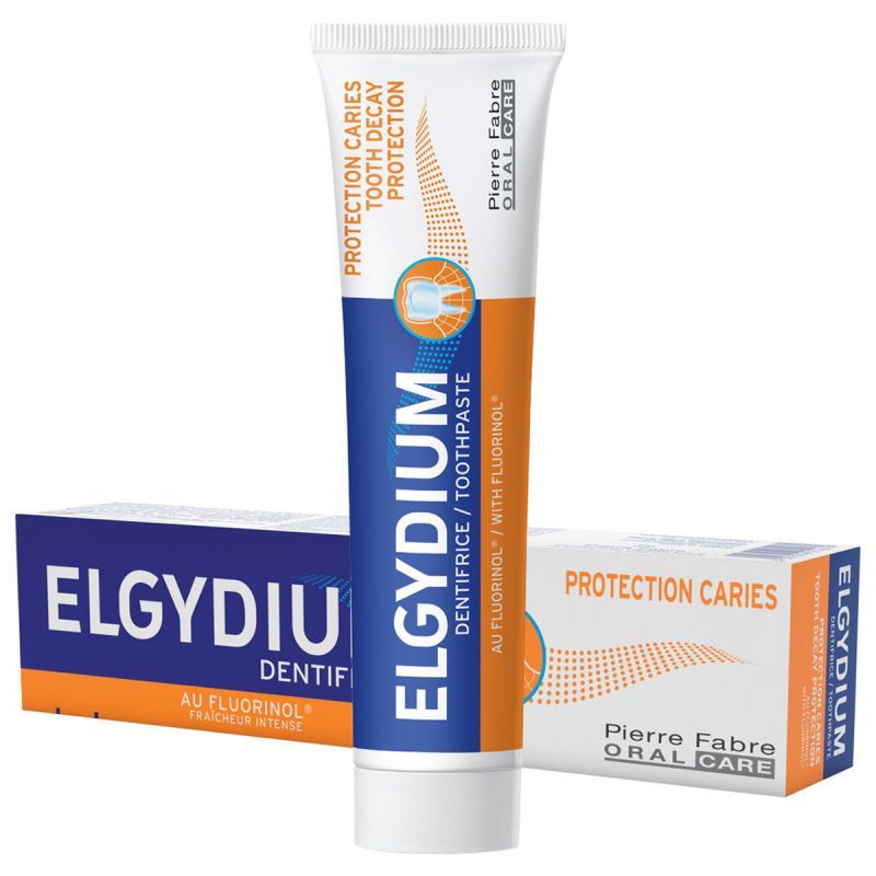 Caja y tubo de pasta dentífrica ELGYDIUM, envase blanco, azul y naranja sobre fondo blanco.