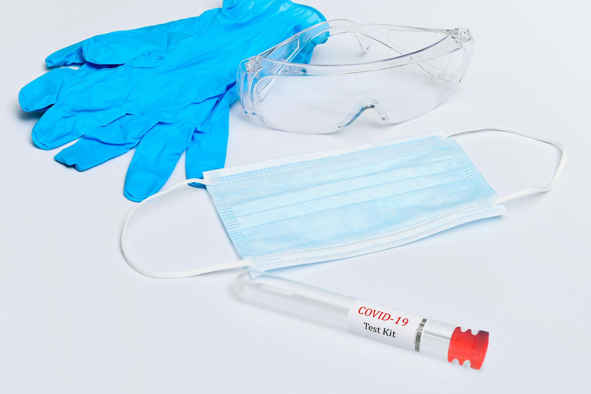 Guantes azules, gafas de seguridad transparentes, mascarilla facial azul claro y una jeringa con tapa roja s