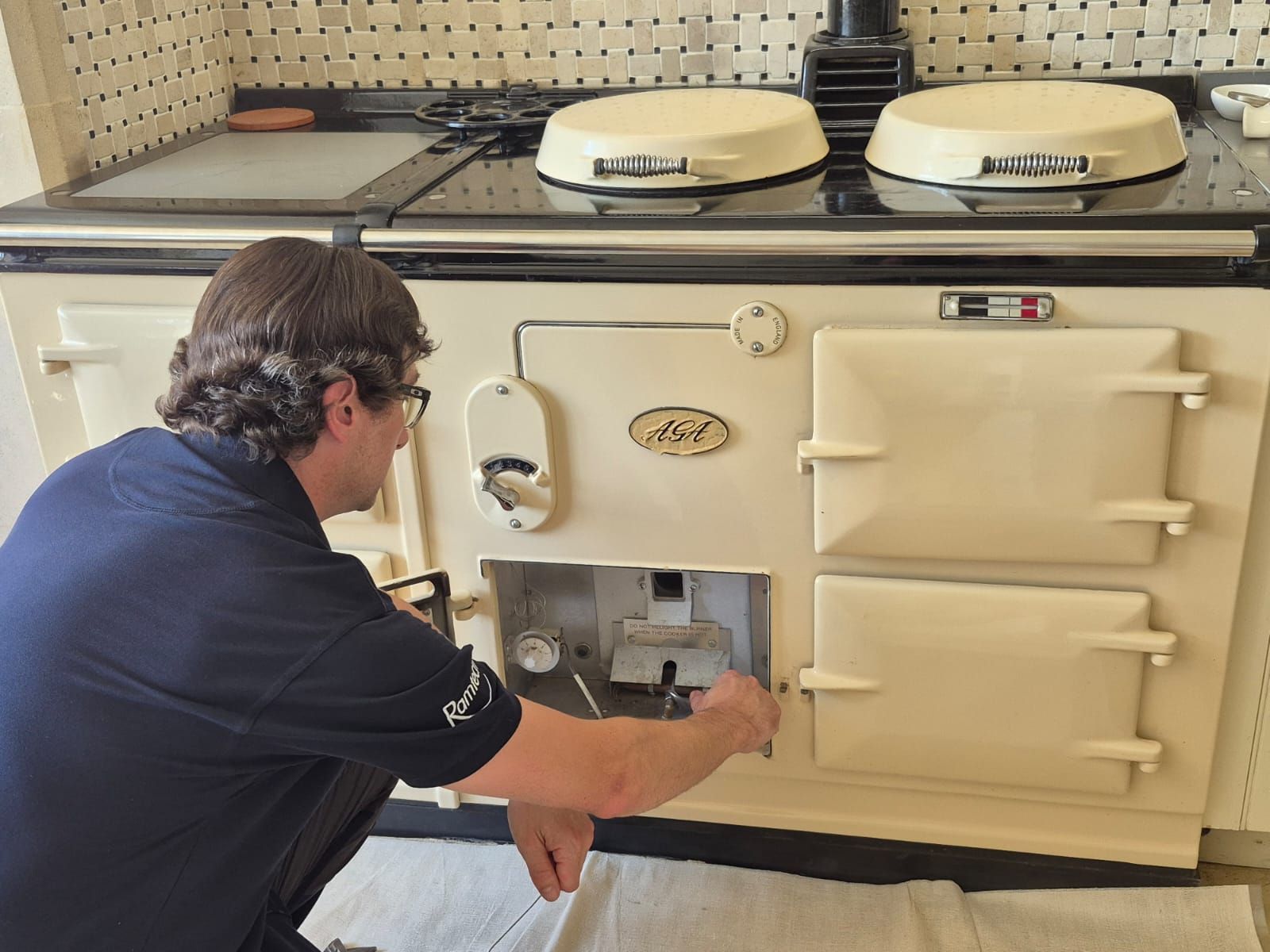 Person opens the lower compartment of a cream-colored industrial oven in a workshop.