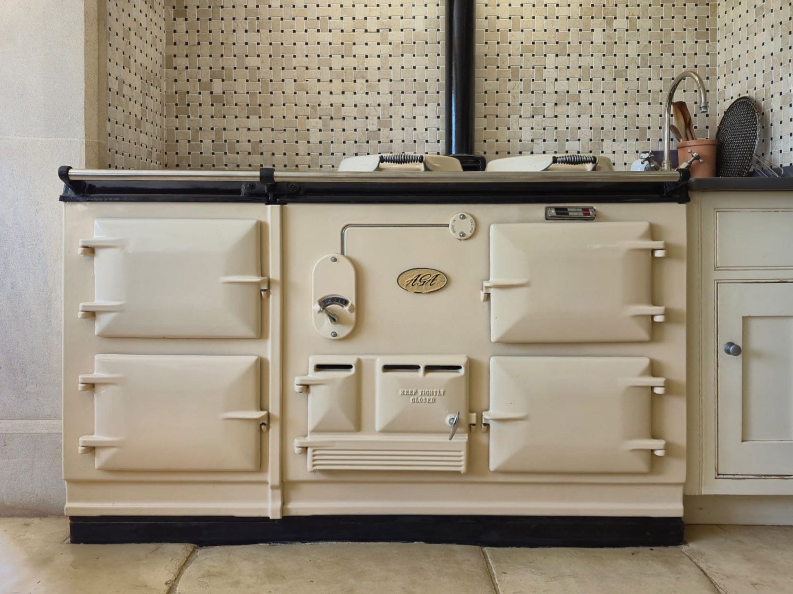 Cream vintage stove with cream cabinets and dark countertop against a tiled kitchen backsplash