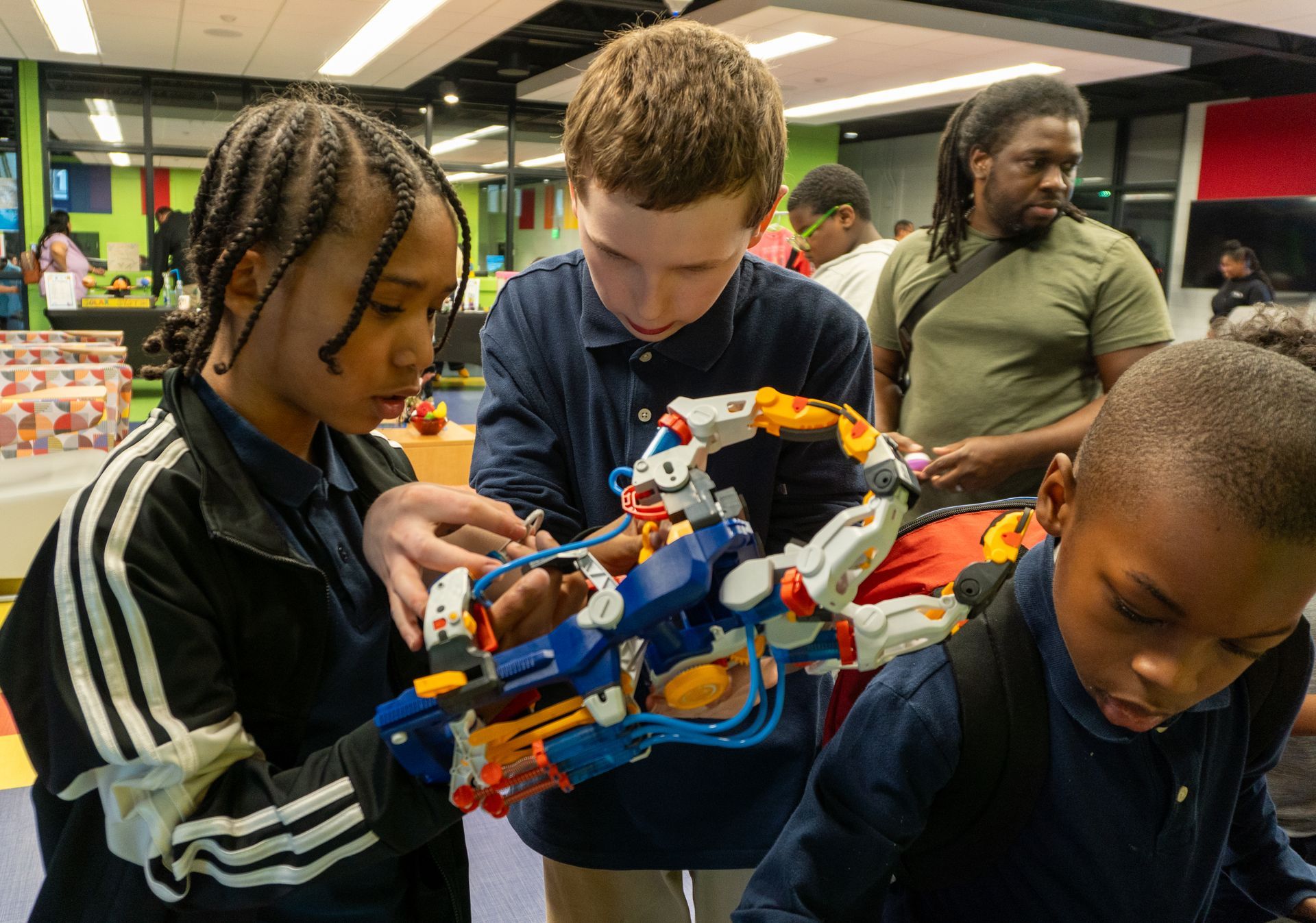 A group of children are playing with a robotic arm.