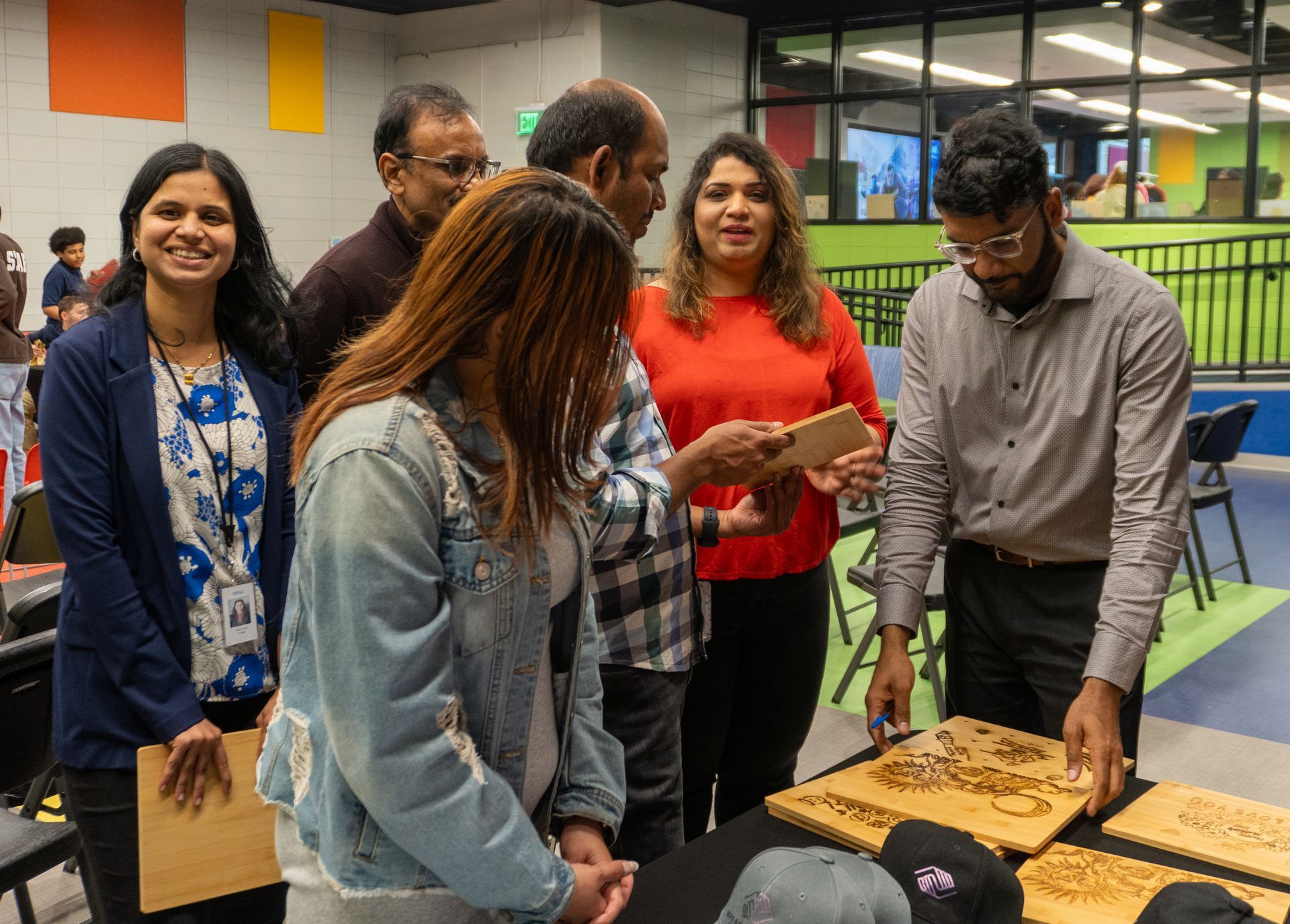 A group of people are standing around a table looking at a piece of wood.