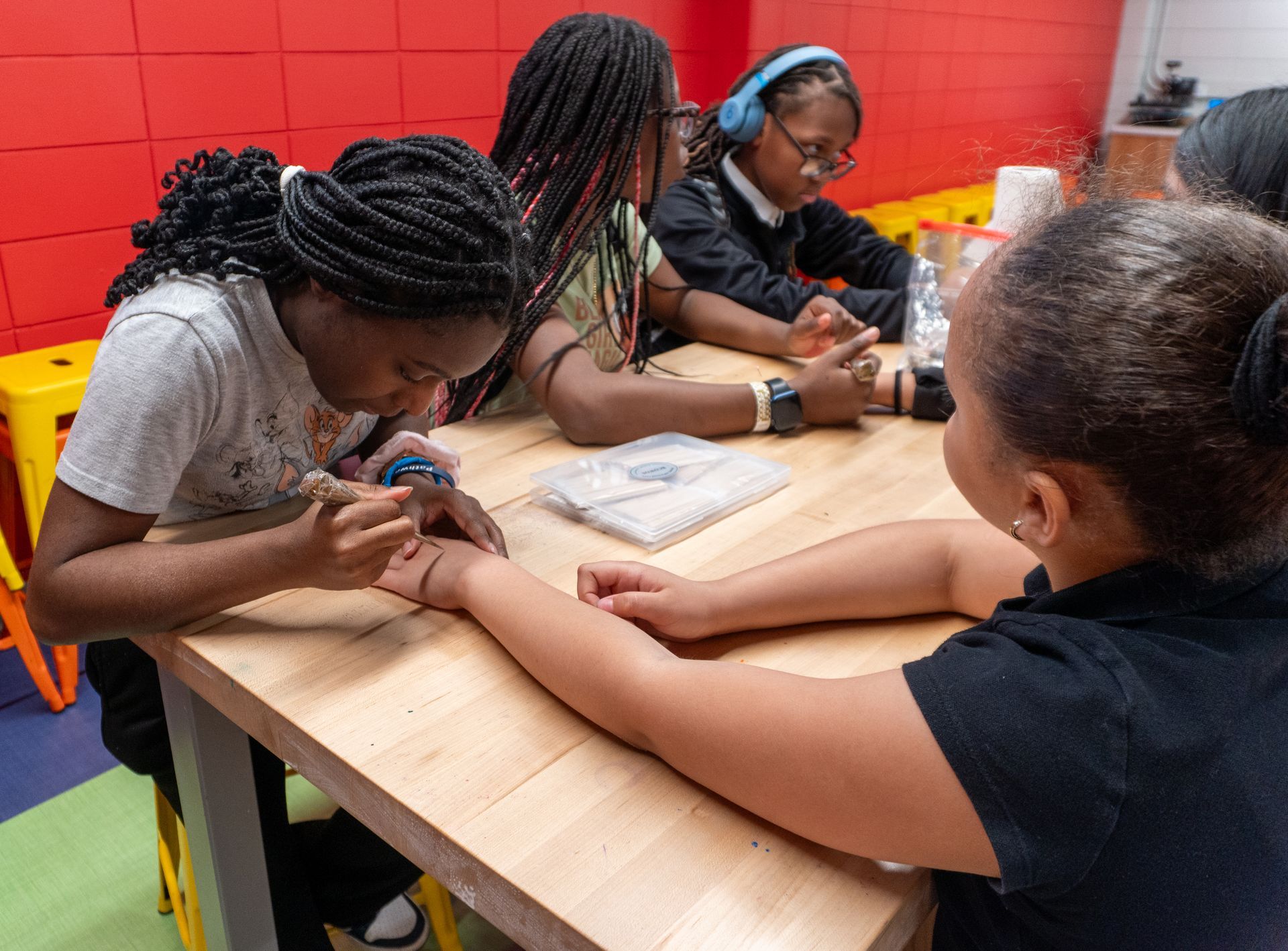 A group of young girls are sitting at a table with their hands on each other.