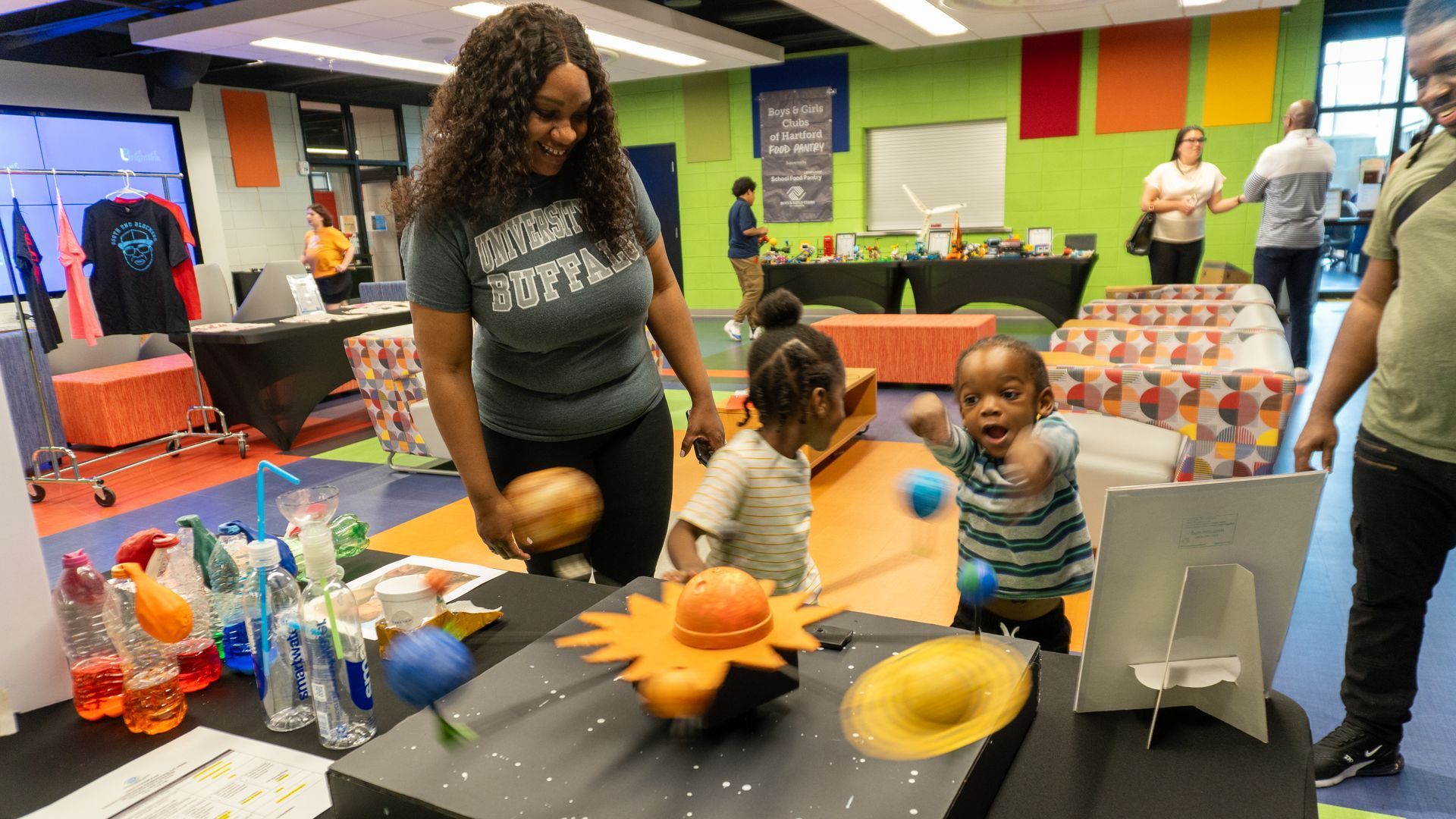 A woman and two children are looking at a model of the solar system.