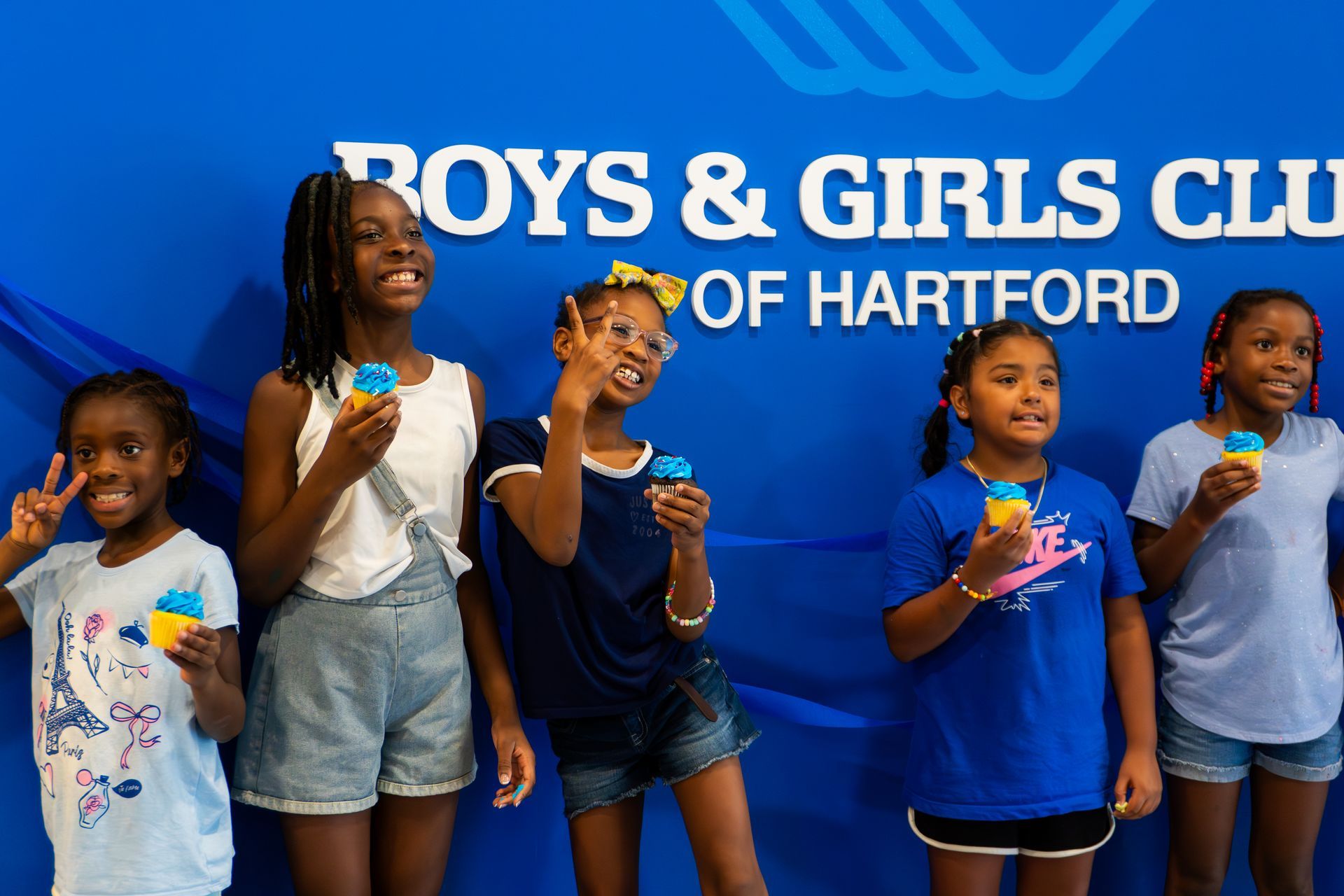 A group of young girls are standing in front of a sign that says boys and girls club of hartford.