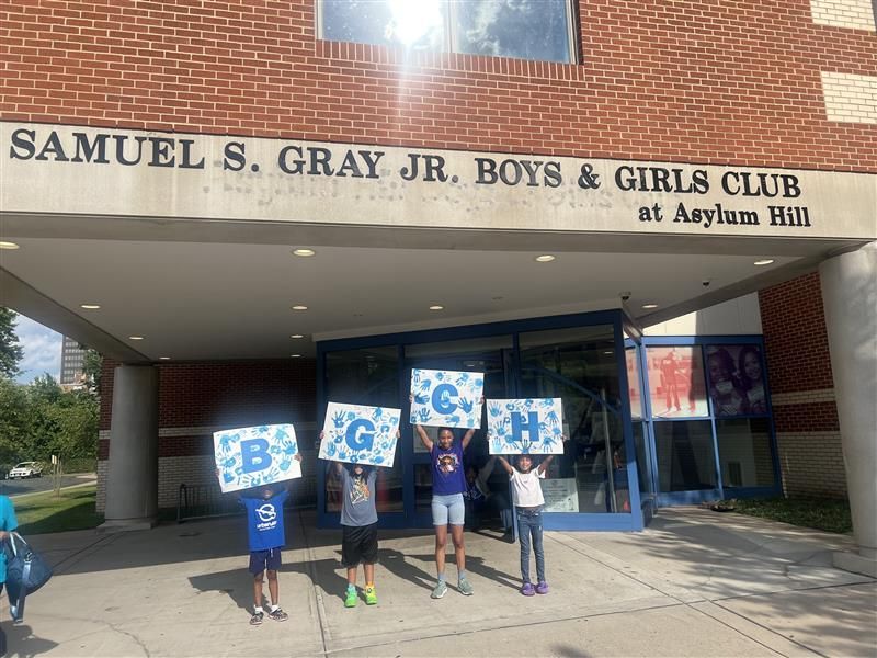 A group of children are holding signs in front of a building.