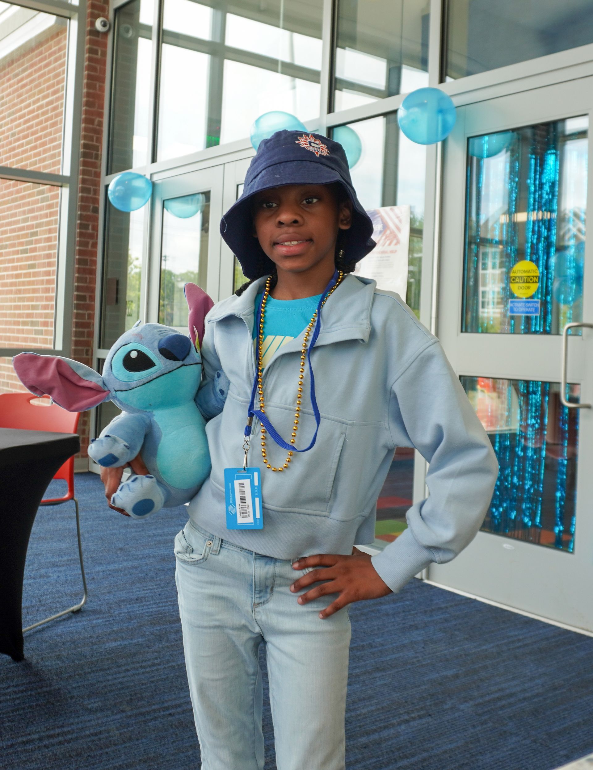 a child dressed in blue holding a stitch doll