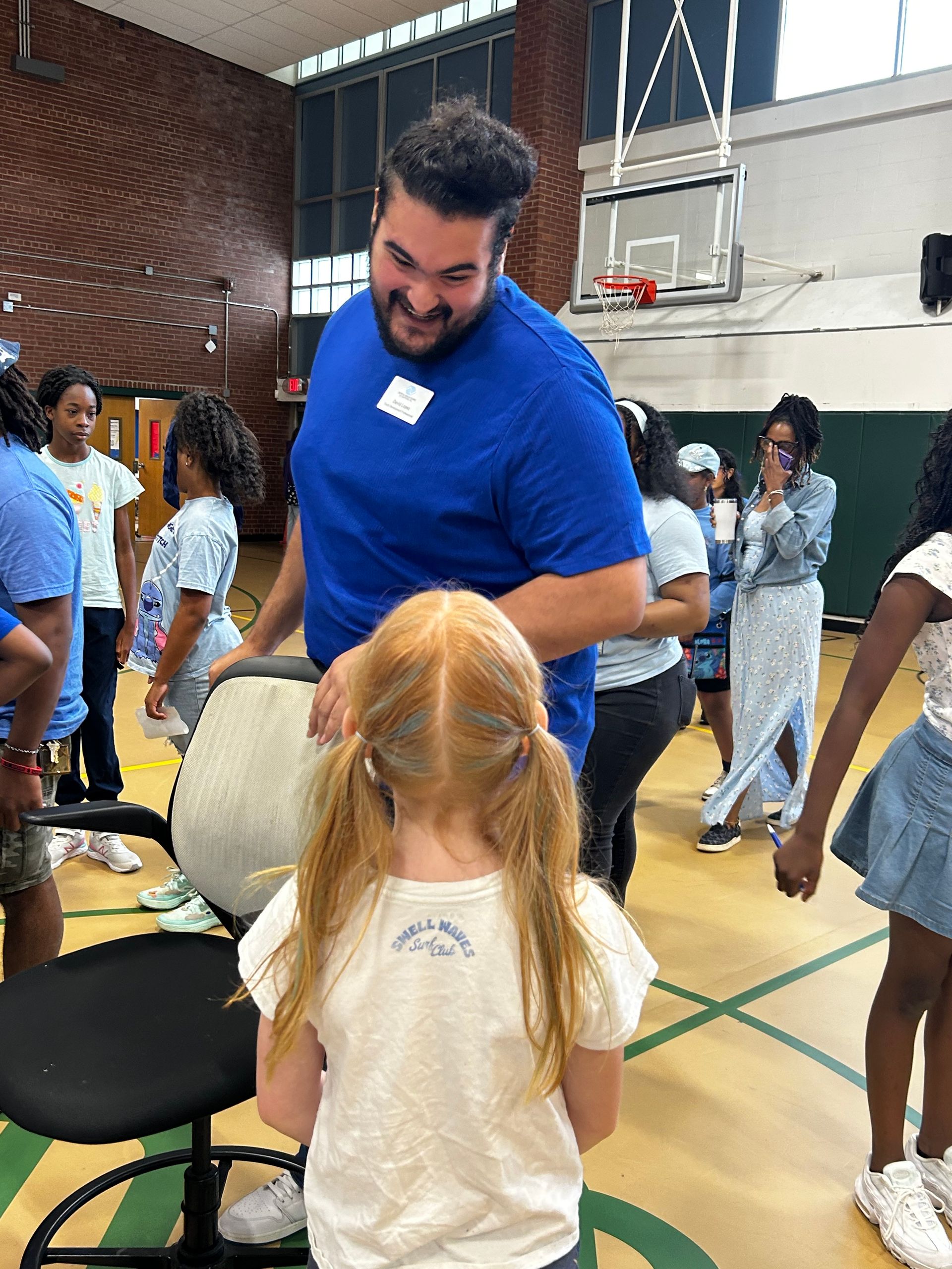A man is standing next to a little girl in a gym.