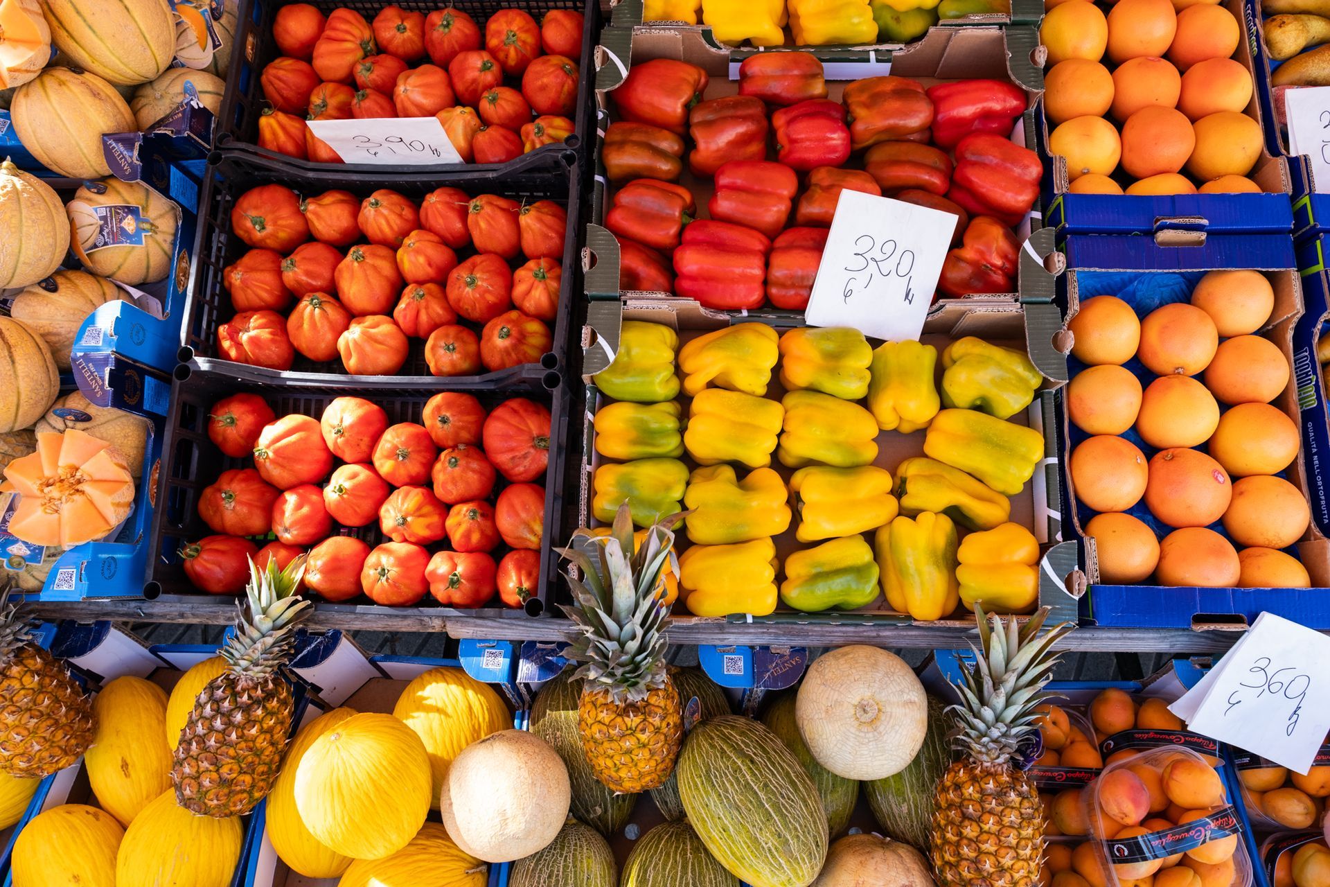 Cassette colorate piene di frutta fresca assortita e ananas in una bancarella del mercato.