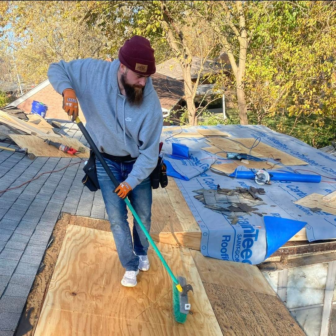 A man is cleaning a roof with a green broom