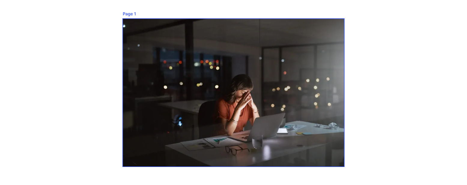 Person sitting at a desk in a dark room, lit by a laptop, looking thoughtful.