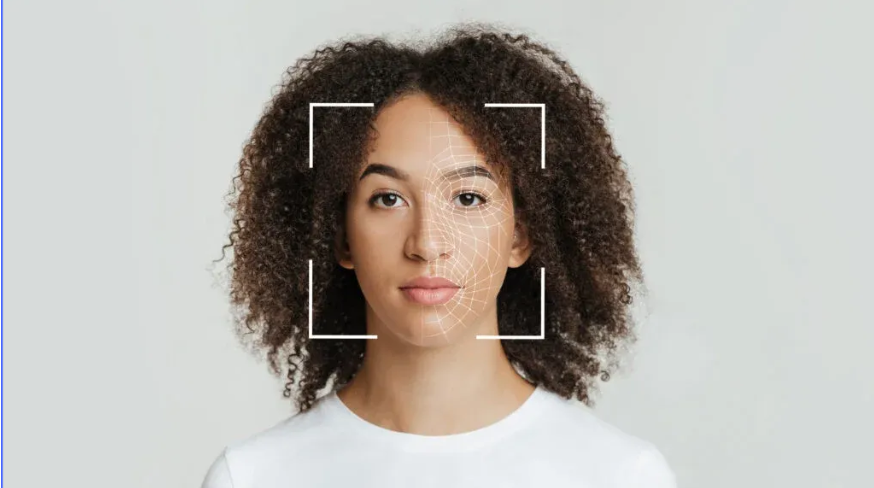 Portrait of a person with curly hair against a light gray background, framed by focus brackets