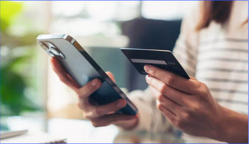 Hands holding a smartphone and credit card, suggesting an online purchase or payment.