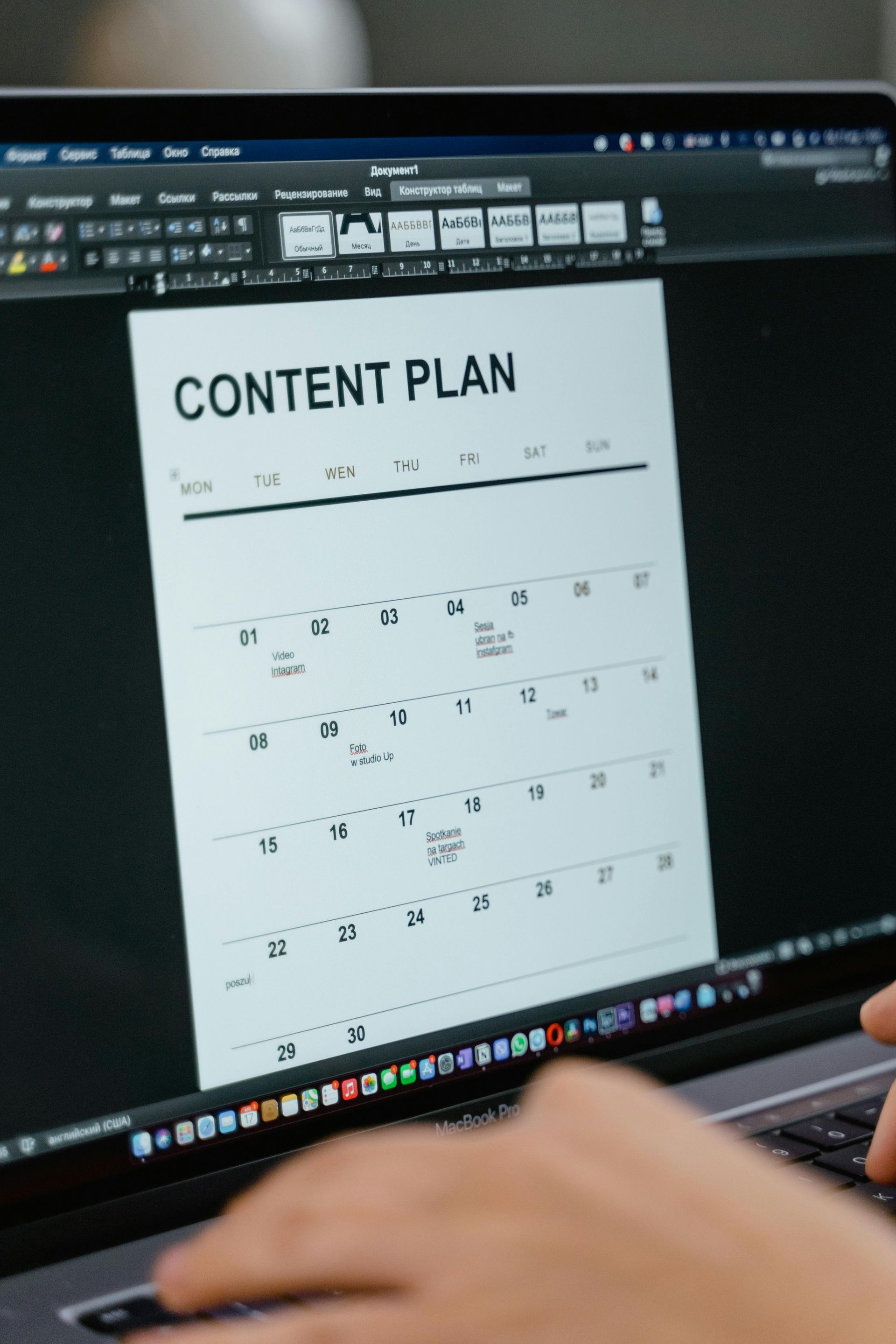 A person is typing on a laptop with a content plan on the screen.