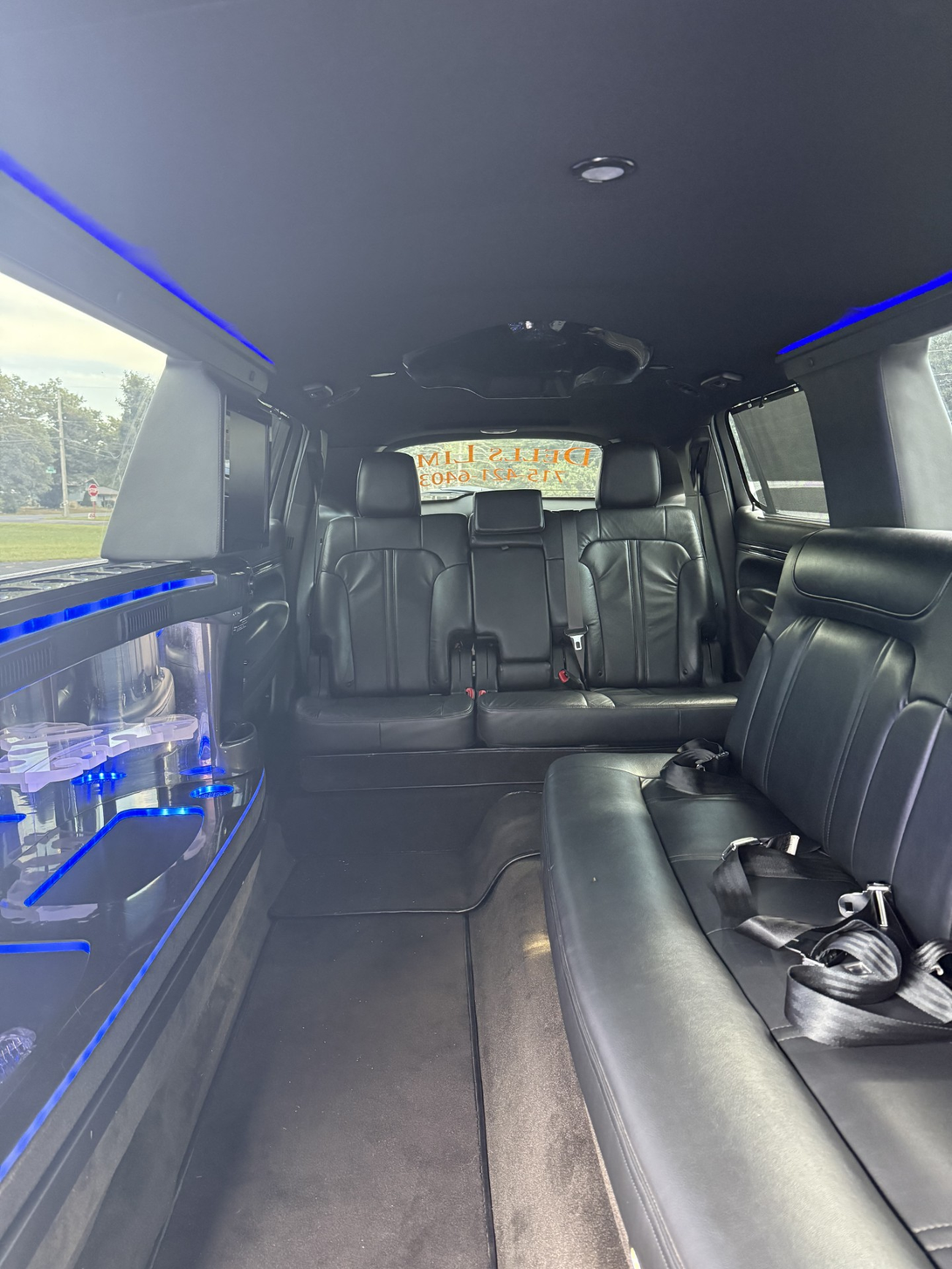 Luxurious limousine interior with black leather seats and glowing wood-trimmed side panel lighting