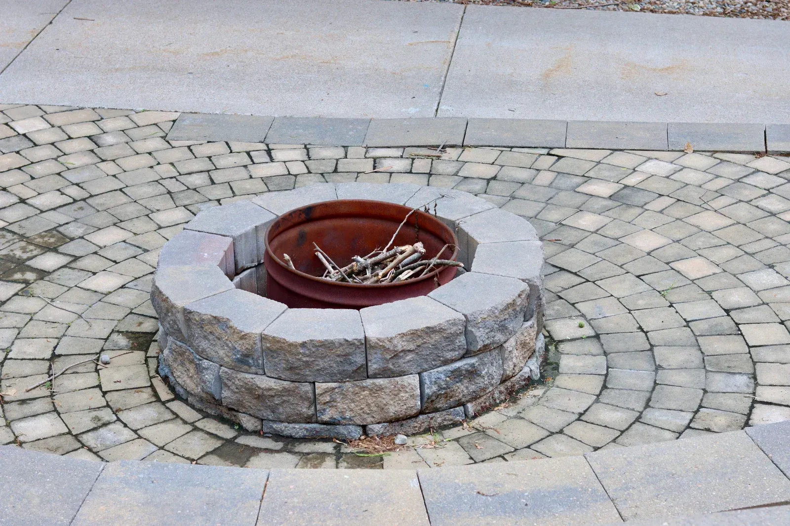 A fire pit is surrounded by bricks on a patio.