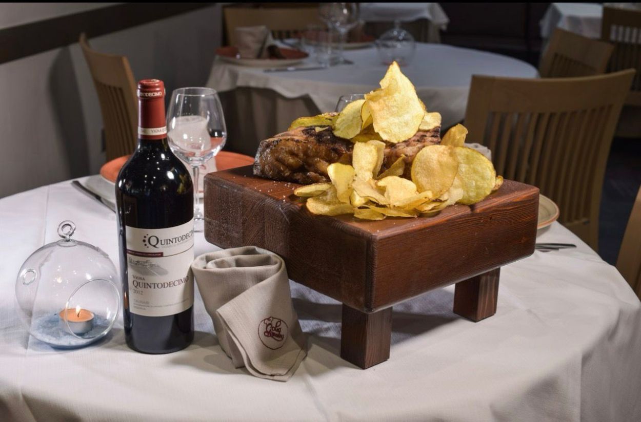 Scaffali con un assortimento di bottiglie di vino e liquori in una vetrina illuminata da una luce calda.